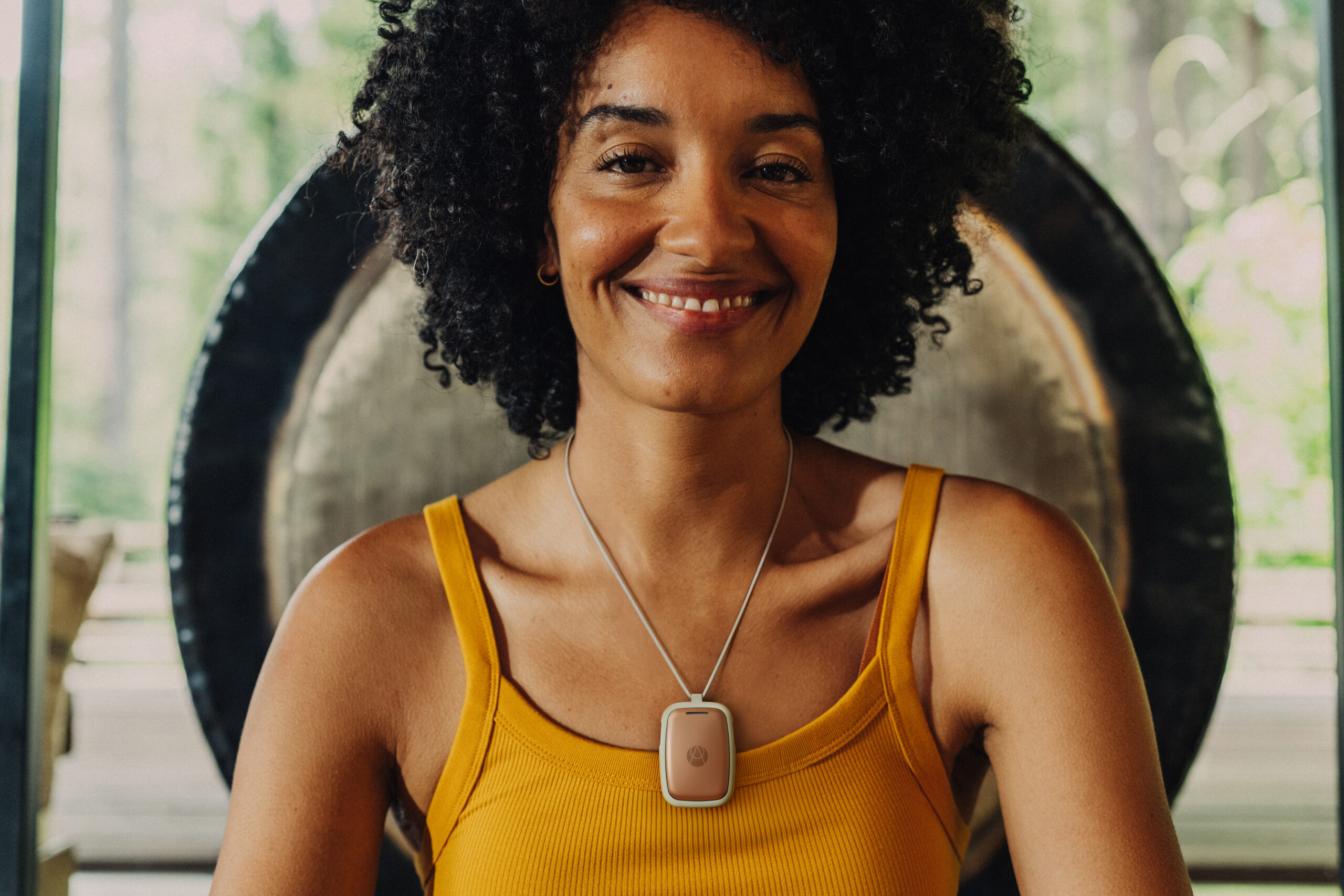 Happy middle aged woman wearing Apollo 2.0 lifestyle pendant with SmartVibes exuding calm inside and balance.