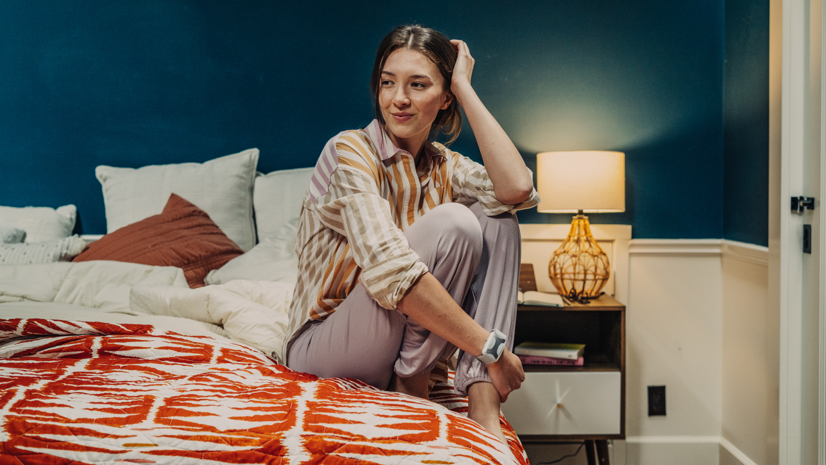 Apollo Wearable On Wrist. Woman Sitting on Bed. Sleep soundly. Wake up stronger.