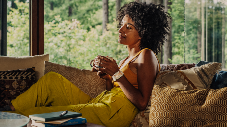 Apollo Calm Inside Woman Resting on couch with Apollo Wearable on Wrist.